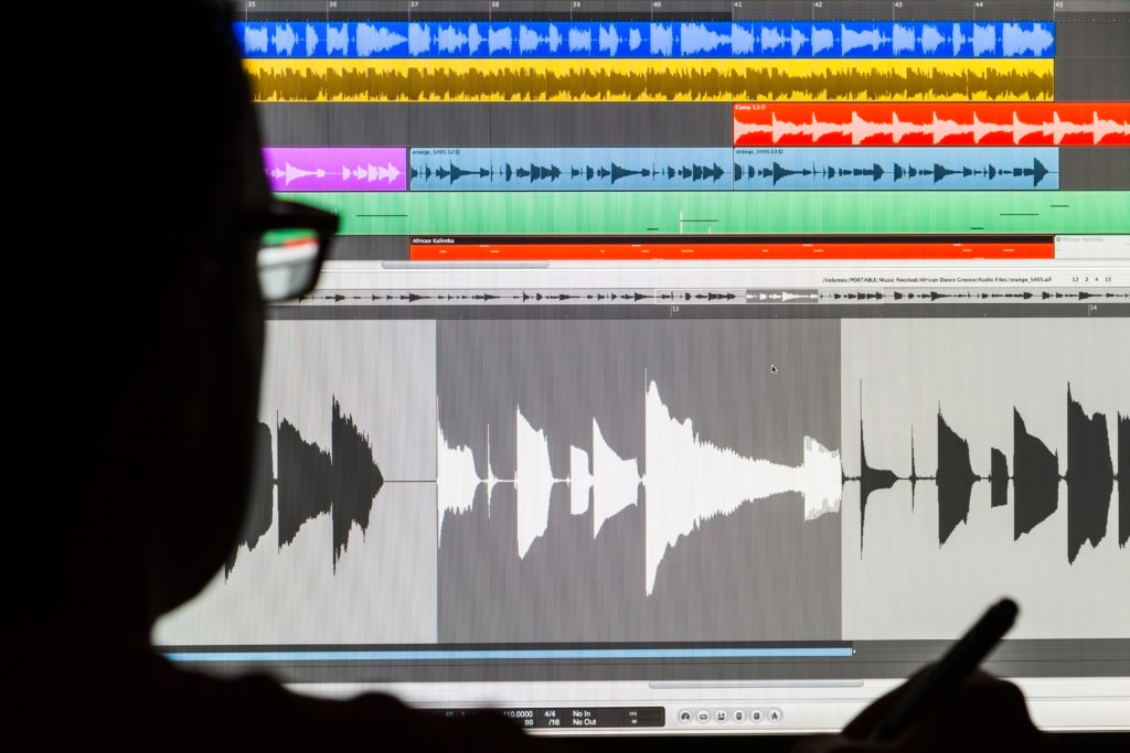 Silhouette of a man using a Digital Audio Workstation to edit sound