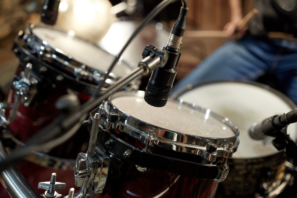 musical instruments and entertainment concept - drums and microphone at music studio